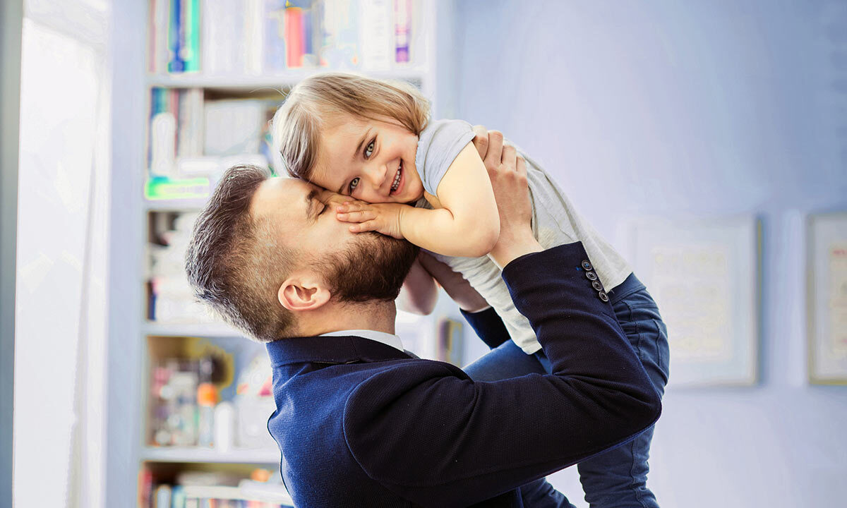 image of man holding little girl and kissing her on the cheek
