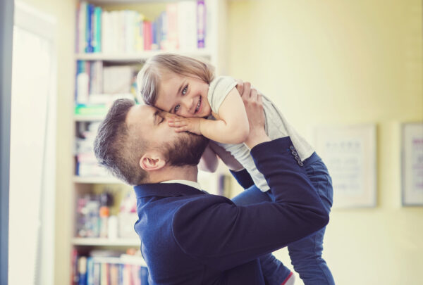image of man holding little girl and kissing her on the cheek